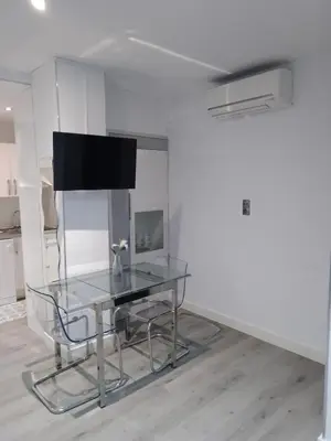 a glass table in a white room with a tv at Sitges Oasis in Sitges