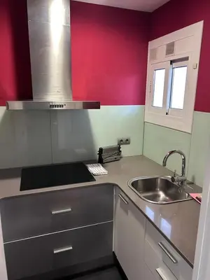 a kitchen with a sink and a red wall at Mery Castelldefels Beach in Castelldefels