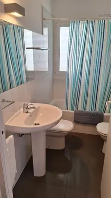 a bathroom with a sink and a toilet and a window at Cozy apartment next to the beach in Sitges