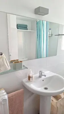 a white bathroom with a sink and a mirror at Cozy apartment next to the beach in Sitges