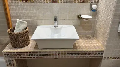 a bathroom sink with a faucet on a tiled counter at Apartamento precioso en primera línea de mar in Les Botigues de Sitges