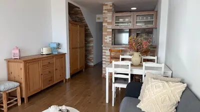 a kitchen and living room with a table and chairs at Apartamento precioso en primera línea de mar in Les Botigues de Sitges