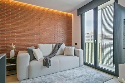 a living room with a couch and a brick wall at 3 Bedroom Cozy Apartment In Joan Austria in Barcelona