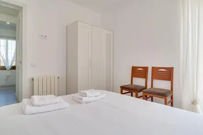 a bedroom with a white bed and two chairs at Guest Ready‑Bright & Stylish Flat with 3 Terraces in Barcelona