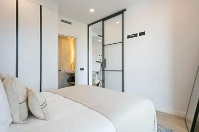 a bedroom with a white bed with glass doors at 1 Bedroom Cozy Aparment Joan Austria in Barcelona