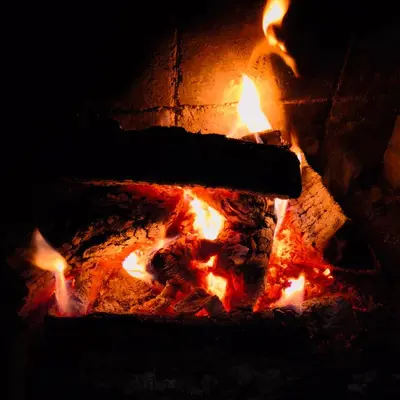 a fire in a brick oven with flames at El Roserar Cabaña de Madera y Caravana Vintage Parque Natural del Montseny in Montseny