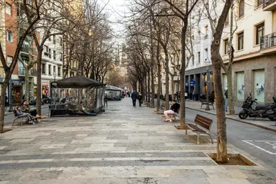 a city street with people sitting on benches and trees at Whisper-Quiet 2BR Near Sagrada in Barcelona