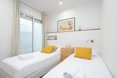 two beds in a room with a window at Canela Homes BARCELONA MERCÈ in Barcelona