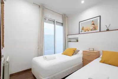 two beds in a room with a window at Canela Homes BARCELONA MERCÈ in Barcelona