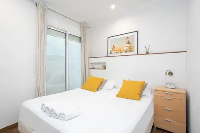 a white bedroom with a bed and a window at Canela Homes BARCELONA MERCÈ in Barcelona