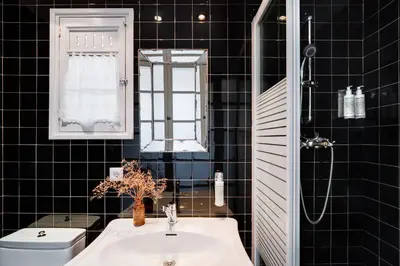a black tiled bathroom with a sink and a toilet at Brummell Apartments Gracia in Barcelona