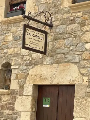 a sign on the side of a stone building with a door at Cal correu Hort - Xida in Collsuspina