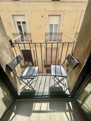 two chairs sitting on a balcony in front of a building at Ven una temporada al centro de Barcelona in Barcelona