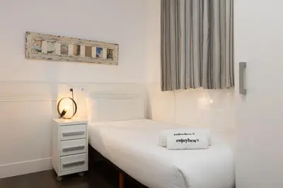 a small bedroom with a white bed and a window at Enjoybcn Coliseum Apartments in Barcelona