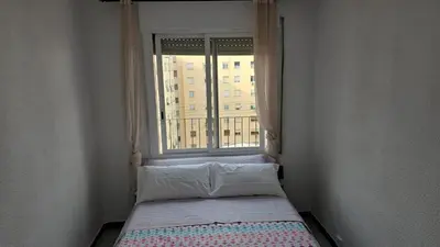 a small bed in a room with a window at A 10 de sagrada familia minutos caminando in Barcelona
