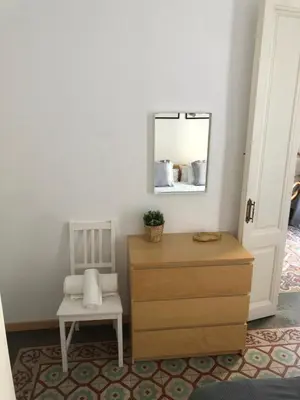a bedroom with a dresser and a mirror and a chair at 1 Casual Apartments in Barcelona