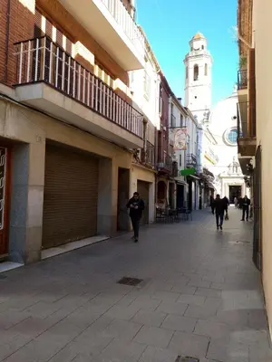 a man walking down a street with a clock tower at Charming traditional family townhouse in Calella in Calella