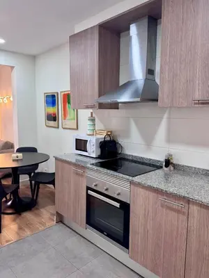 a kitchen with a stove top oven next to a table at Apartamento Lauda 2 in Hospitalet de Llobregat