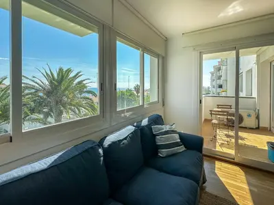 a living room with a blue couch and large windows at Viva Palms by Hello Homes Sitges in Sitges