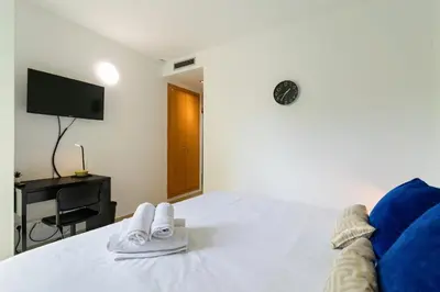 a bedroom with a bed with a tv and two slippers at Carol Suites Fira Barcelona Habitaciones privadas en apartamento in Hospitalet de Llobregat
