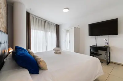 a bedroom with a large white bed with blue pillows at Carol Suites Fira Barcelona Habitaciones privadas en apartamento in Hospitalet de Llobregat