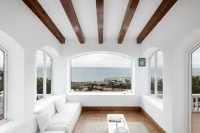 a living room with a white couch and large windows at Exclusive Villa with Private Pool in Sitges in Sitges