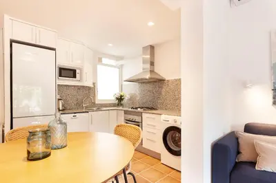 a kitchen and living room with a table and a couch at Casa Rosari I - Jardín & Parking Privado in Vilassar de Mar