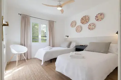 a white bedroom with two beds and a window at Rosari II - Vivienda Privada con Parking in Vilassar de Mar