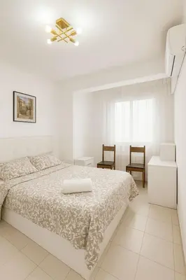 a white bedroom with a bed and two chairs at New renovate apartment near of the sea in Barcelona