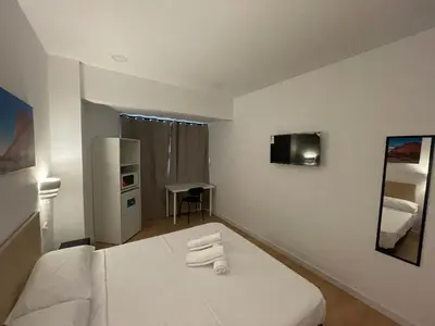 a bedroom with a white bed with towels on it at Lux Hostal in Hospitalet de Llobregat