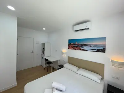 a white bedroom with a bed and a desk at Lux Hostal in Hospitalet de Llobregat