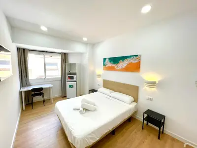 a bedroom with a white bed and a desk at Lux Hostal in Hospitalet de Llobregat