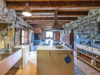 a large kitchen with a stone wall at Farmhouse near Barcelona with Pool in Marganell
