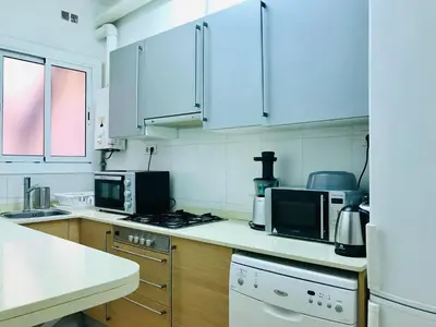 a kitchen with white appliances and wooden cabinets at Modern and Elegant Barcelona Apartment in Barcelona