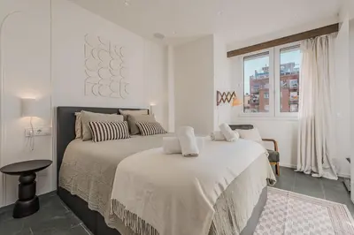a white bedroom with a large bed and a window at Sant Joan Design Apartment in Barcelona