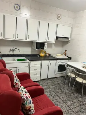 a kitchen with white cabinets and red chairs and a table at Casa EMILIO in Olesa de Montserrat