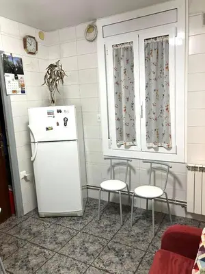 a kitchen with a white refrigerator and two chairs at Casa EMILIO in Olesa de Montserrat
