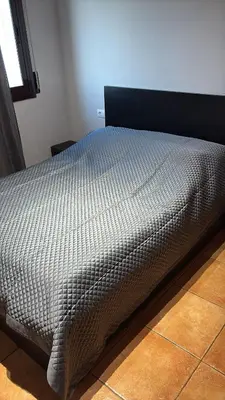 a bed in a bedroom with a gray comforter at Calle Ramon Berenguer Iv, 13, Sant Pere de Ribes barcelona 08812 in Vilanova i la Geltrú
