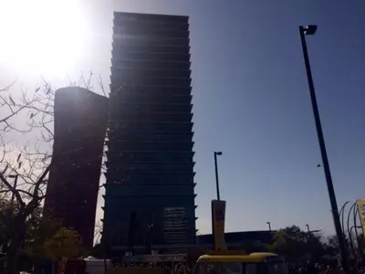 a tall building in a city with the sun behind it at 3-Apartament full equiped, next to Mobile Congres in Hospitalet de Llobregat