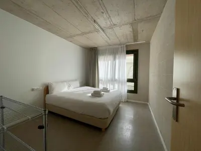a bedroom with a white bed and a window at Mooeve Montjuïc in Barcelona