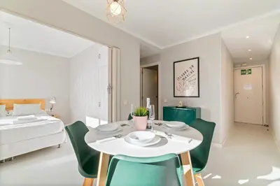 a dining room with a white table and green chairs at Marblau Beach Vacation and Downtown Sitges in Sitges