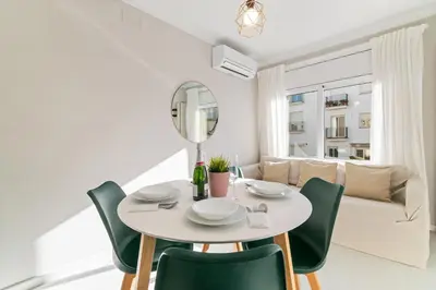 a white dining room with a table and green chairs at Marblau Beach Vacation and Downtown Sitges in Sitges