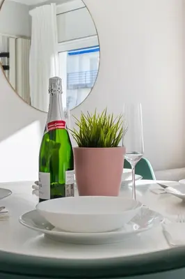 a table with a green bottle and a plate and a glass at Marblau Beach Vacation and Downtown Sitges in Sitges