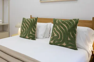 a bed with green and white pillows on it at Stay U-nique Apartment Passeig d´Amunt in Barcelona