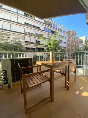 a table and bench on a balcony with a building at Centric Apartment with Balcony in Barcelona
