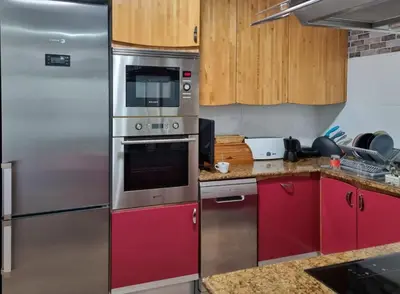 a kitchen with red cabinets and stainless steel appliances at Voramar, Apartamento a primera línea de mar y con piscina in Canet de Mar