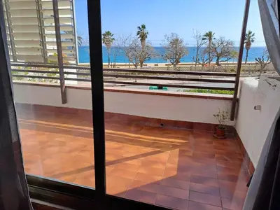 a room with a view of the beach from a balcony at Voramar, Apartamento a primera línea de mar y con piscina in Canet de Mar