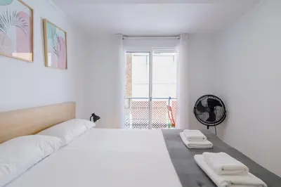 a white bedroom with a large bed with two towels at Apartamento Completo junto playa y Centro Bcn in Badalona