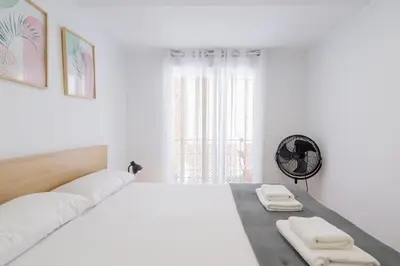 a white bedroom with a large bed and a window at Apartamento Completo junto playa y Centro Bcn in Badalona