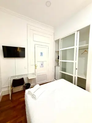 a white bedroom with a bed and a tv on the wall at Hotelito Luxe in Barcelona